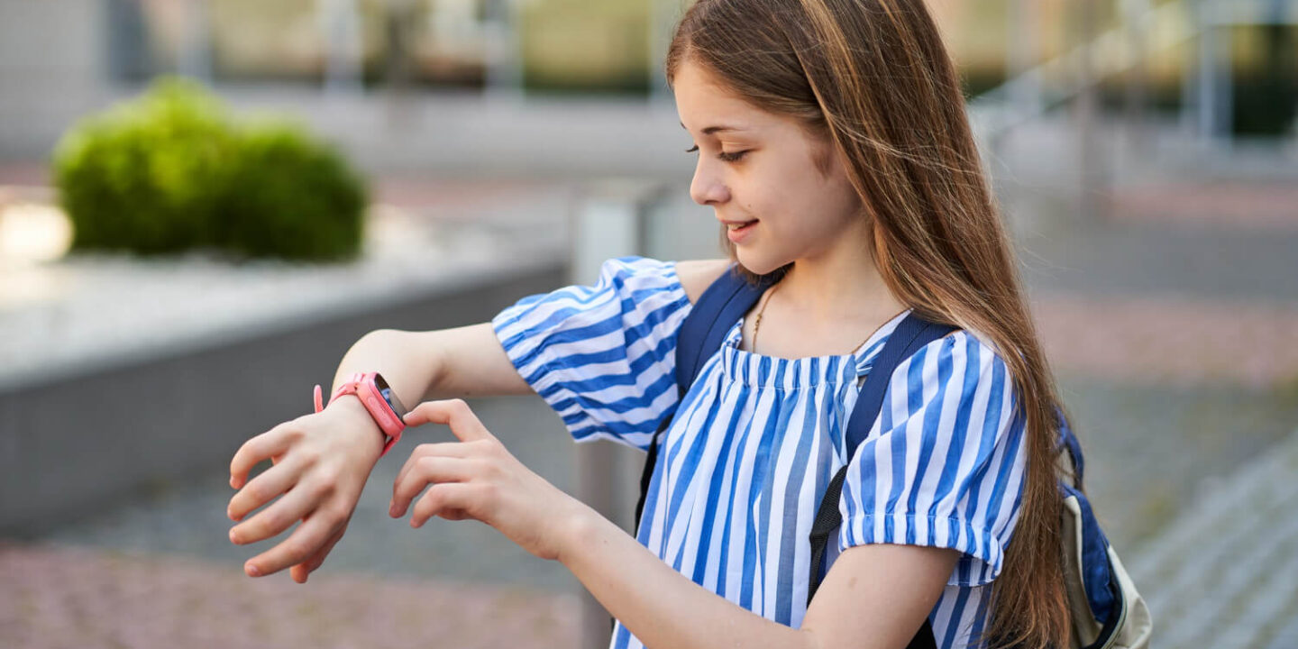 young-kid-girl-make-video-call-her-parents-with-her-pink-smartwatch-near-school